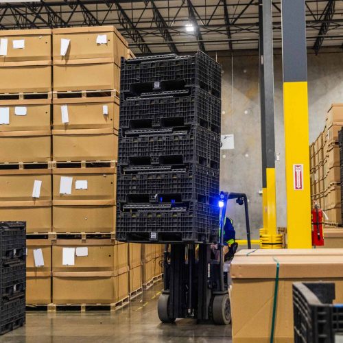 A warehouse worker lifting pallets with a forklift.