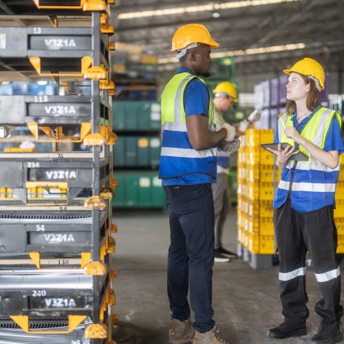 Two warehouse workers taking inventory of automotive batteries.