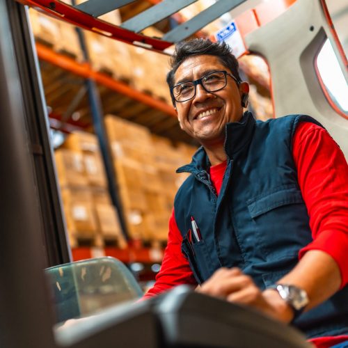 Happy warehouse worker using a forklift.