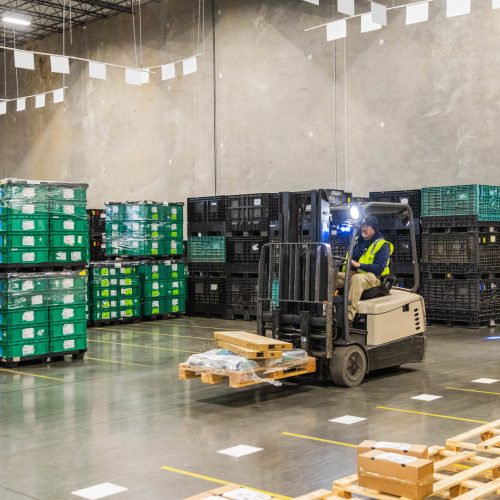A warehouse worker moving goods around with a forklift.